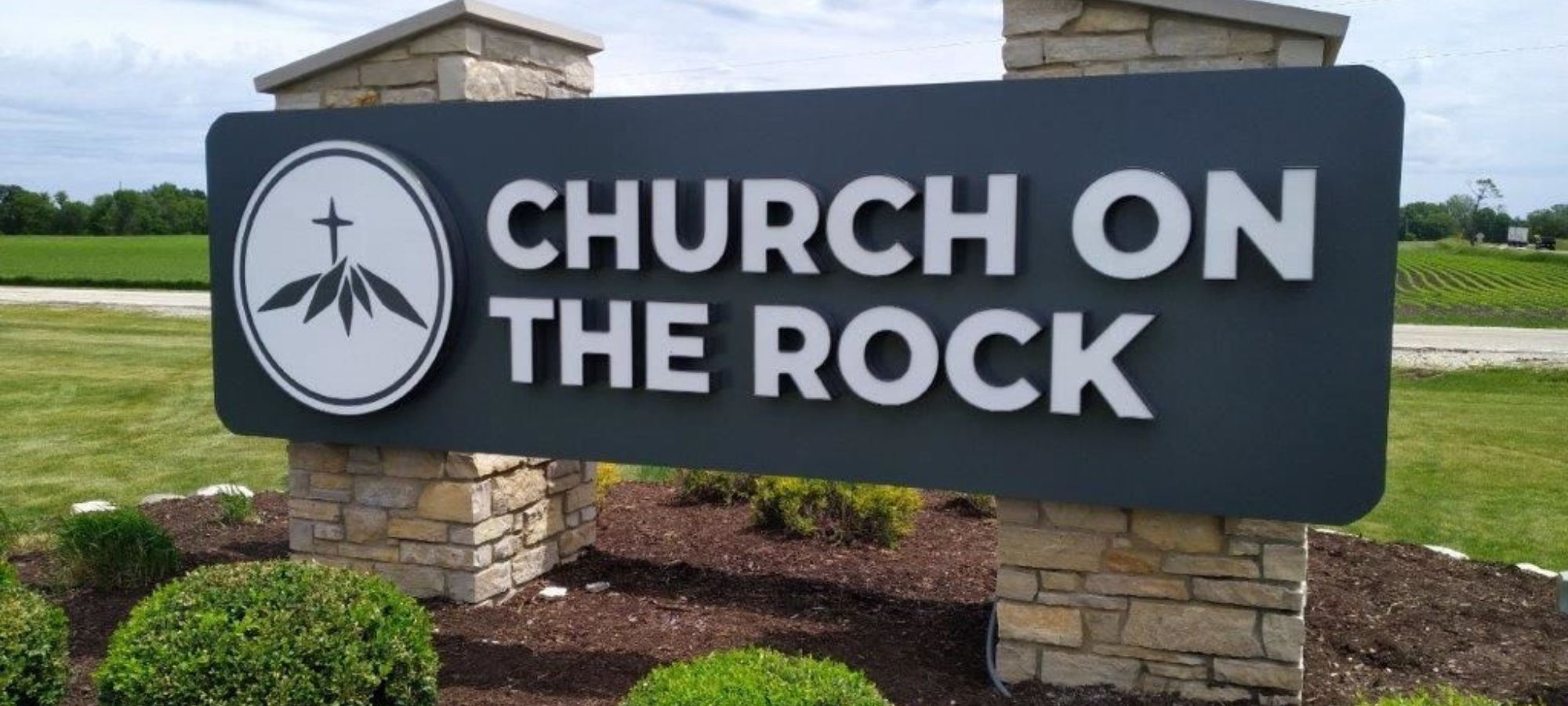 A large monument sign reading "Chuch on the Rock" in white letters on a black background